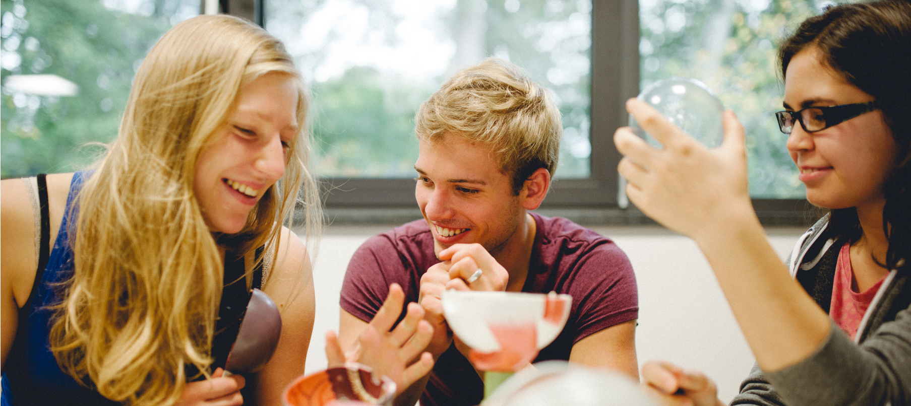 Das Foto zeigt zwei Schülerinnen und einen Schüler, denen das Lernen Freude macht.